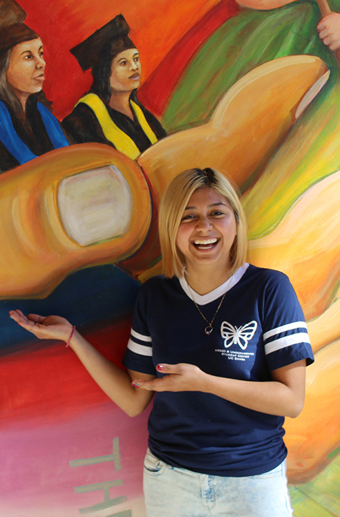 Estefania Sinay Pacheco poses in front of a mural UC Davis Aggie Hero