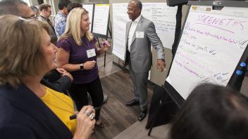 Chancellor may laughs with colleagues in front of large note pads as they brainstorm a strategic vision for UC Davis.