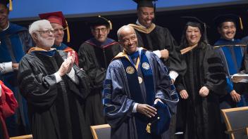 Chancellor Gary May in cap and gown is celebrated at his Investiture at UC Davis, while faculty and staff cheer him on. 