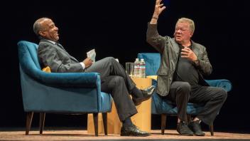 Chancellor May laughs as William Shatner raises his hand in a large gesture at UC Davis. 