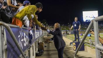 Chancellor May shakes the hands of people in the bleachers. 