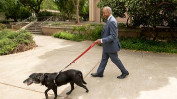 Photo of Chancellor Gary May walking a black dog with a pepper-colored snout
