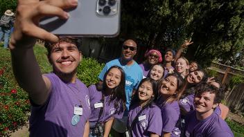Photo of a student taking a group selfie with Chancellor Gary May and other students