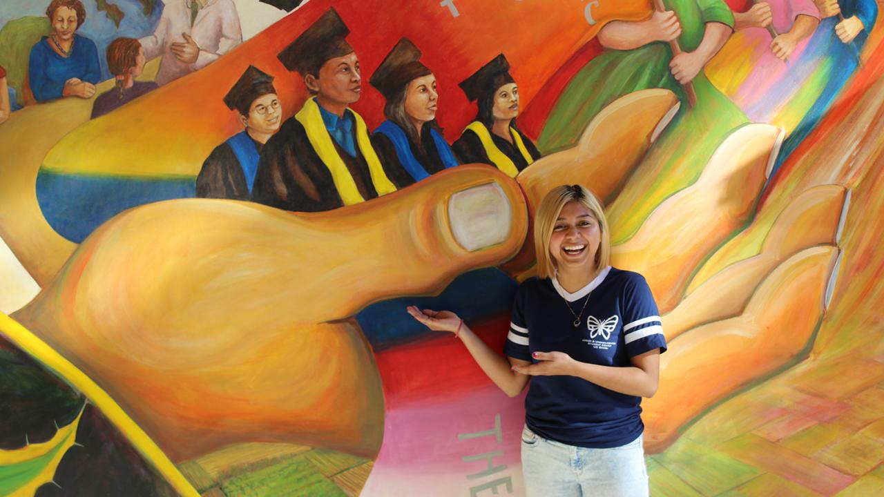 Estefania Sinay Pacheco poses in front of a vibrant mural.