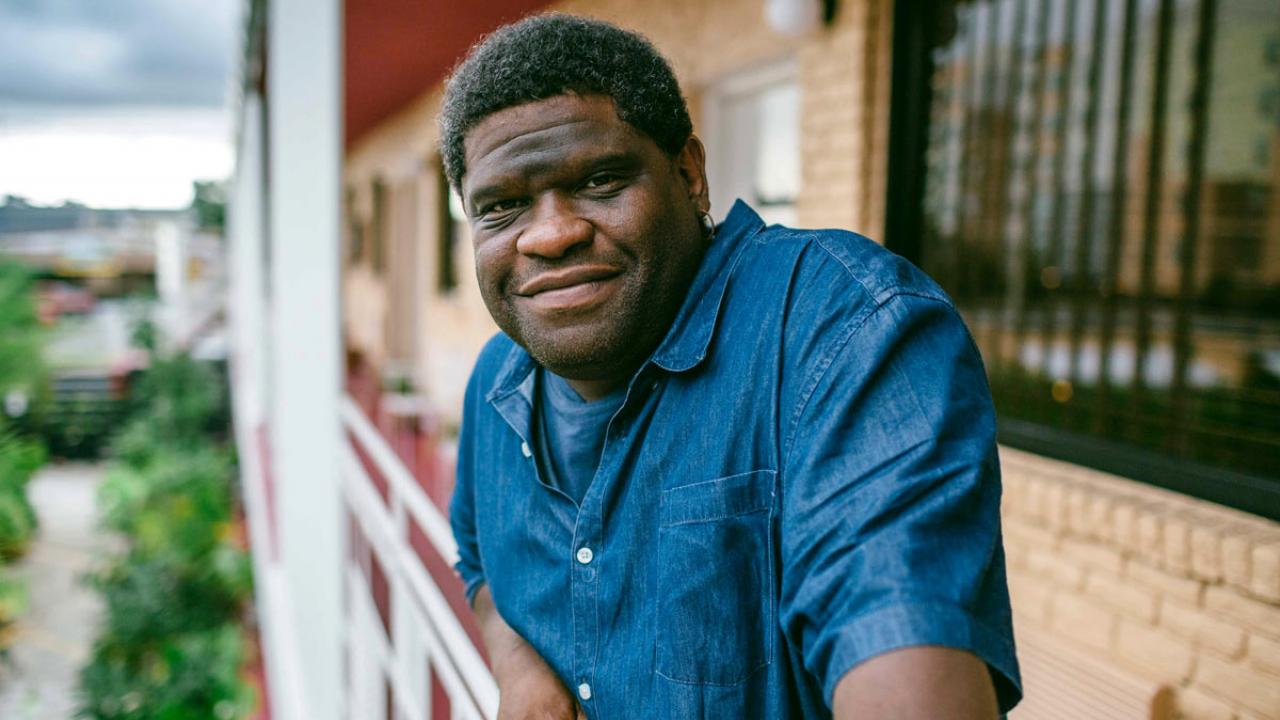 Gary Younge on balcony, environmental portrait