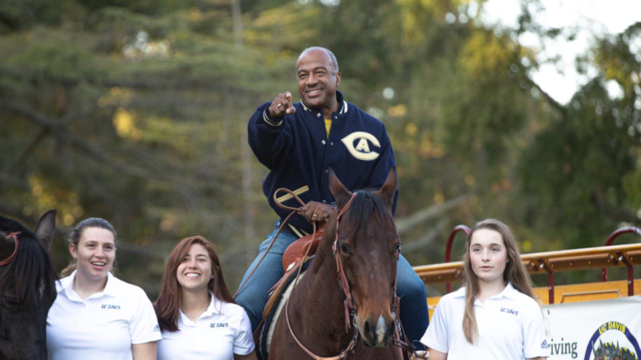 The chancellor rides a horse and points during a holiday celebration at UC Davis. 