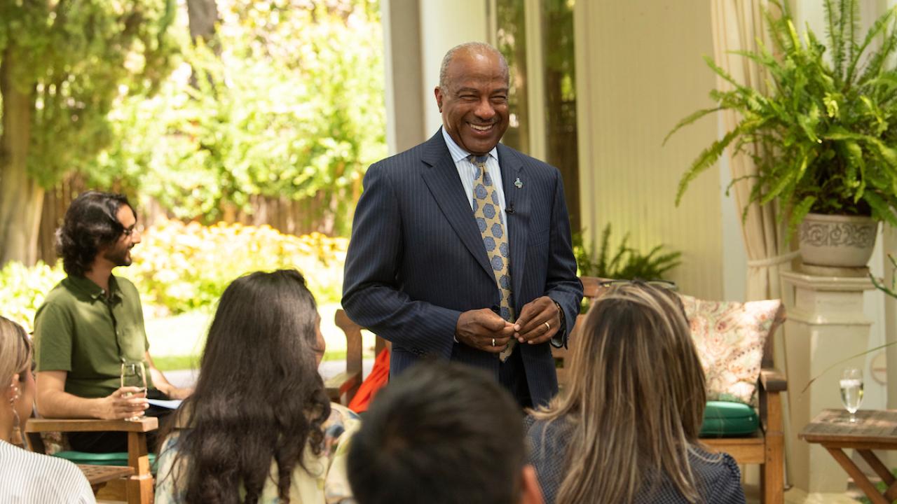 Chancellor May addresses audience outside in the residence courtyard.