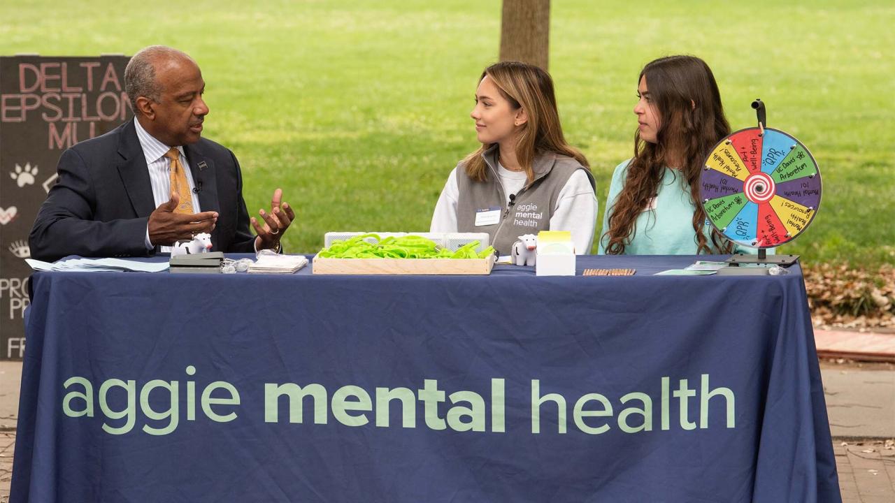 Chancellor May talks with two other individuals at an Aggie Mental Health table.