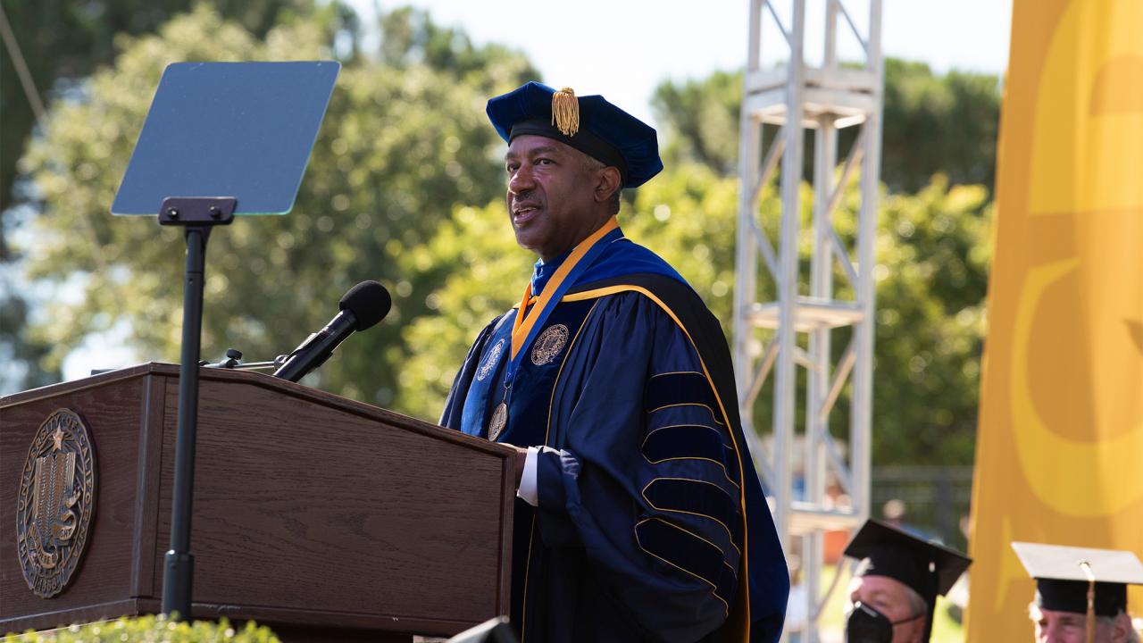 Chancellor May in commencement regalia on stage.