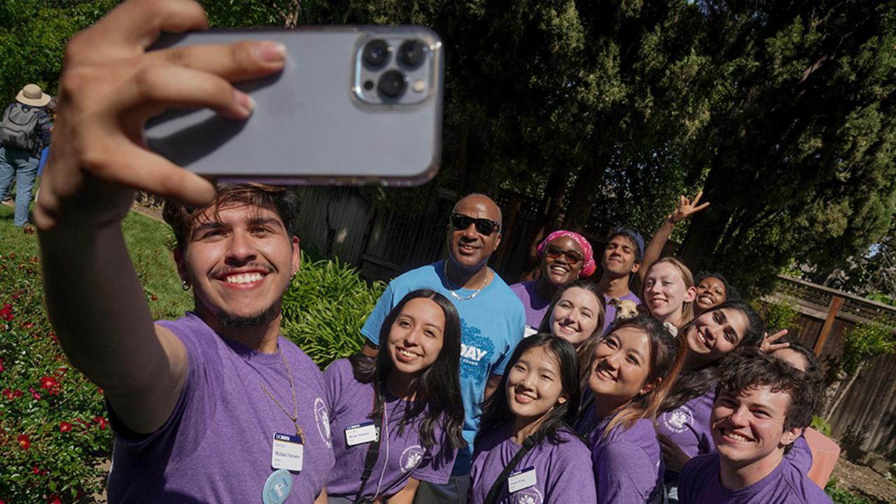 Students holding camera phone taking selfie with Chancellor May