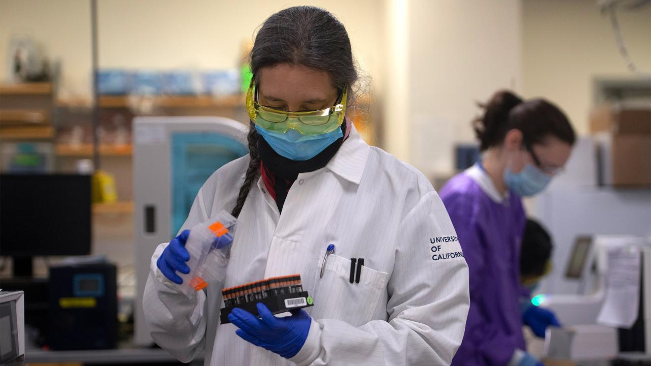 Charlotte Acharya, a staff research associate, holds a tray of samples being tested for COVID-19 at the UC Davis Genome Center.