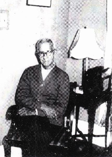 Harrison G. Hunter black and white sitting in living room chair with lamp in background