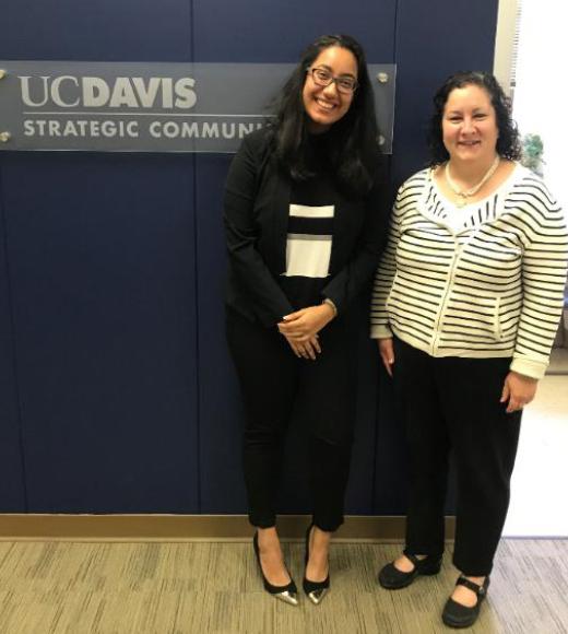 Two people stand next to a sign that reads UC Davis Strategic Communications