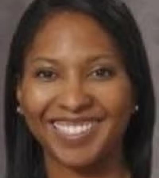Headshot portrait of a smiling woman with straight dark hair and gray background