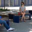 Two UC Davis students sitting socially distanced while wearing face coverings on benches.