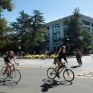 Students ride bicycles in front of Shields Library.