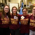 Students pose in a line in kitchen, all wearing burgundy T-shirts with “Challah for Hunger UC Davis” in gold.