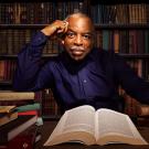 Photo of LeVar Burton in a library, surrounded by books. 