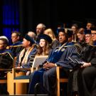 Chancellor Gary May is seated on the stage of the Mondavi Center for the Performing Arts for the School of Law Commencement on May 16, 2025. He is wearing blue and gold regalia and surrounded by Law School faculty and campus leadership.